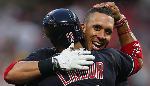 The Cleveland Indians' Francisco Lindor hugs teammate Michael Brantley after Brantley hit a double to score Lindor for a 2-1 win in 10 innings against