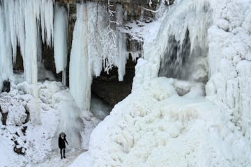 A person prepared to walk down the partially frozen Minnehaha Falls as water still rushed above in 2021.
