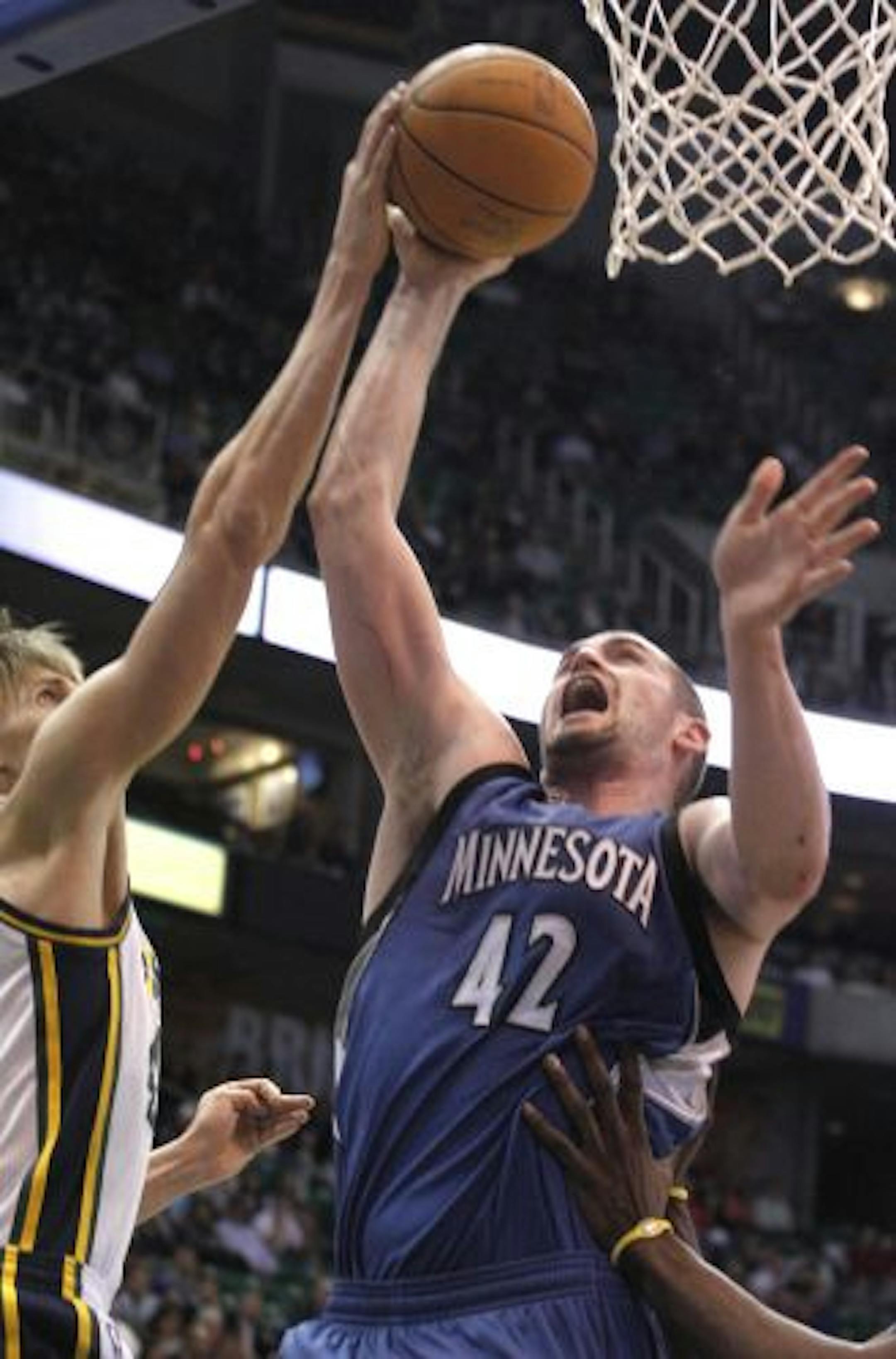 Minnesota's Kevin Love takes a shot as he is defended by Utah's Andrei Kirilenko.