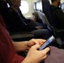 FILE - In this Oct. 31, 2013, file photo, a passenger checks her cell phone before a flight in Boston. The Federal Communications Commission might be 