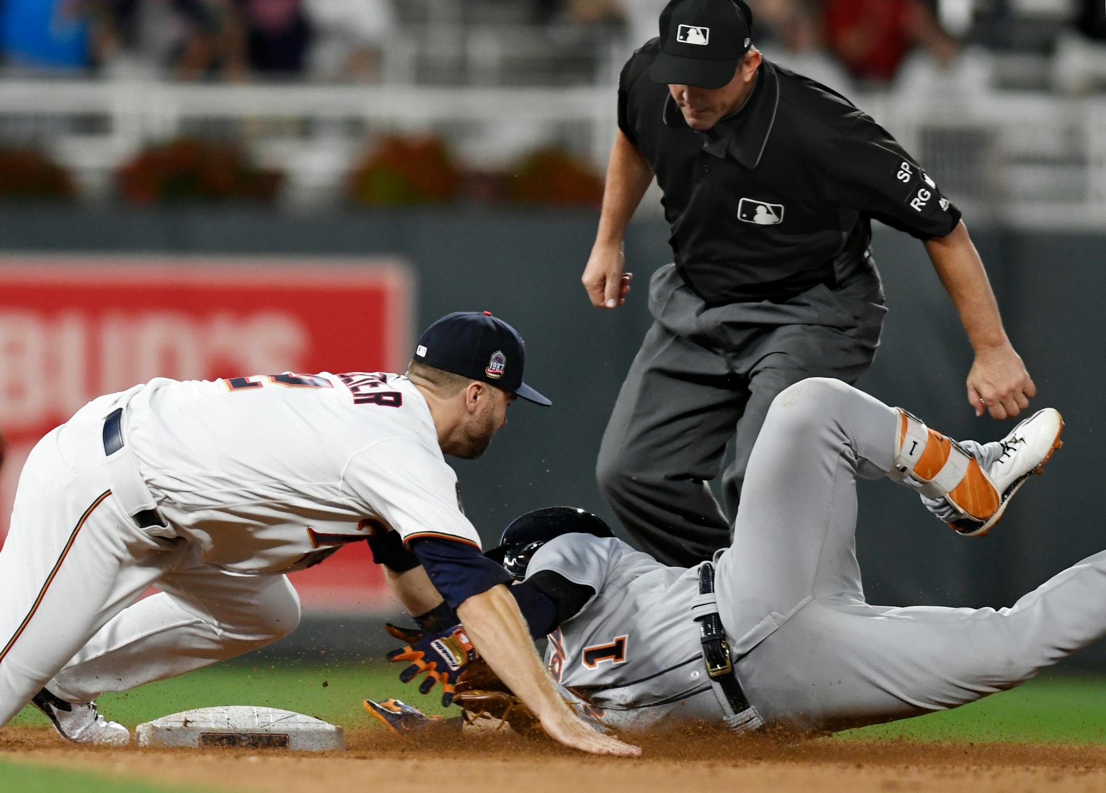 Minnesota Twins second baseman Brian Dozier, left, tags out Detroit Tigers' Jose Iglesias, right, who tried to stretch a single into a double during the ninth inning of a baseball game Saturday, July 22, 2017, in Minneapolis. Second base umpire Jeff Kellogg moves in to make the call. The Twins won 6-5. (AP Photo/Tom Olmscheid)