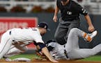 Minnesota Twins second baseman Brian Dozier, left, tags out Detroit Tigers' Jose Iglesias, right, who tried to stretch a single into a double during t