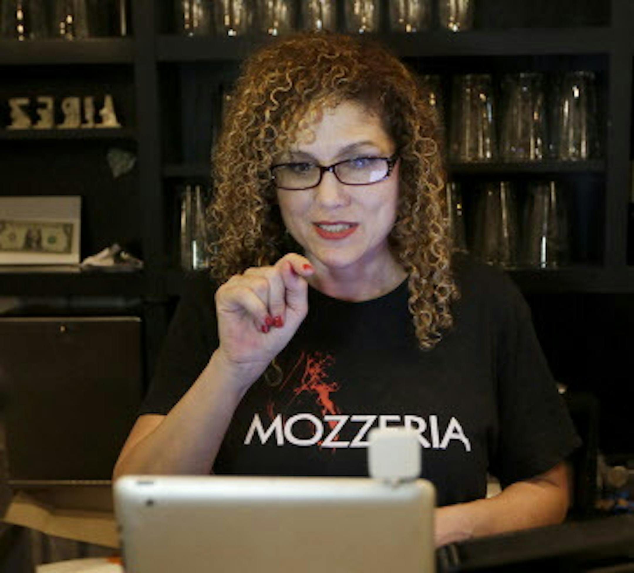 In this Nov. 5, 2015 photo, Tiffany Ruffa uses sign language as she takes call from a customer over a tablet at Mozzeria restaurant in San Francisco. Mozzeria owners Russ and Melody Stein as well as staff workers are deaf. (AP Photo/Jeff Chiu)
