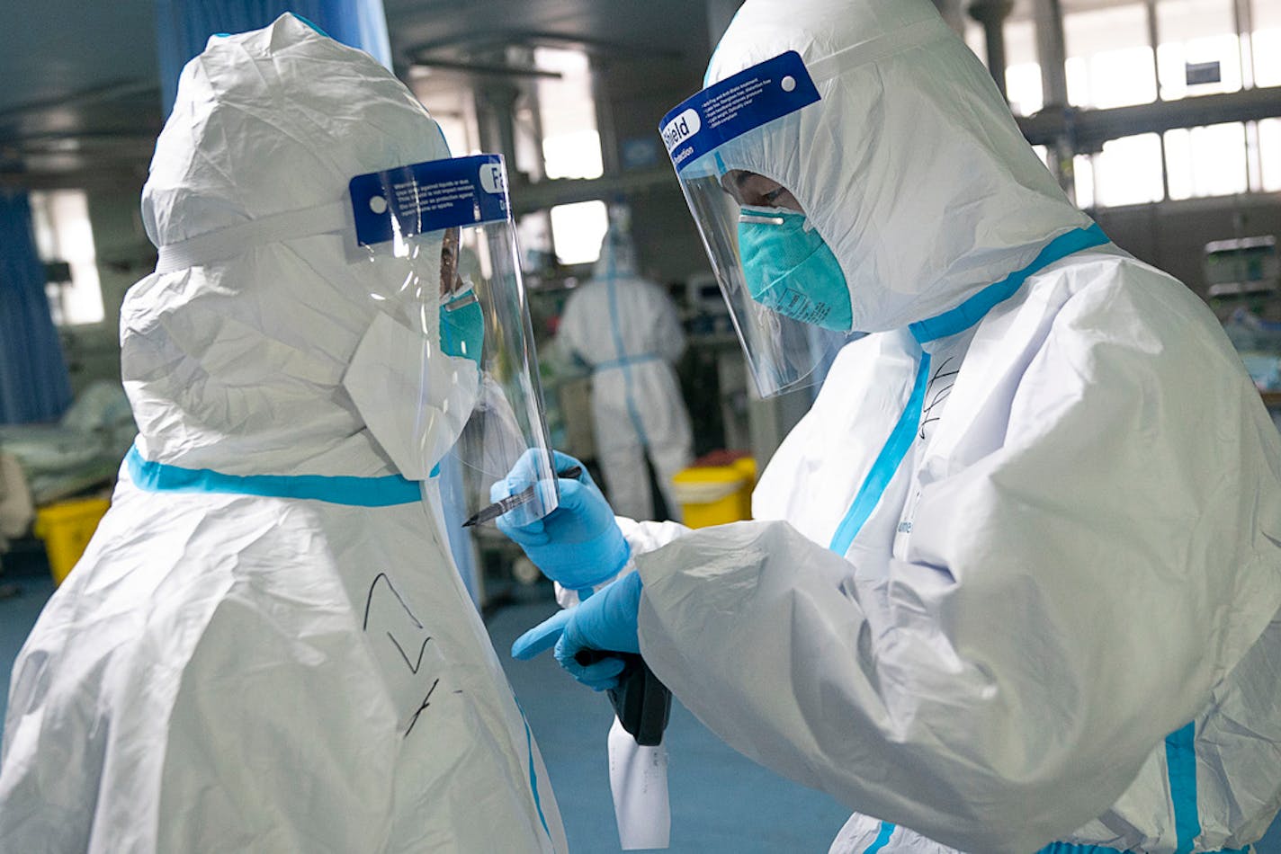 In this photo released by China's Xinhua News Agency, a medical worker writes their colleague's name on a protective suit to aid in identification as they work at Zhongnan Hospital of Wuhan University in Wuhan in central China's Hubei Province, Firday, Jan. 24, 2020.