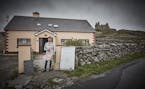 Aine O'Graiofa outside her home and restaurant, with O'Brien's Castle in the background, on Inisheer, County Galway, Ireland, July 2018. Just as in th
