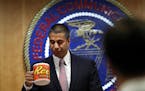 After a meeting voting to end net neutrality, Federal Communications Commission (FCC) Chairman Ajit Pai, takes a sip from his mug while answering ques