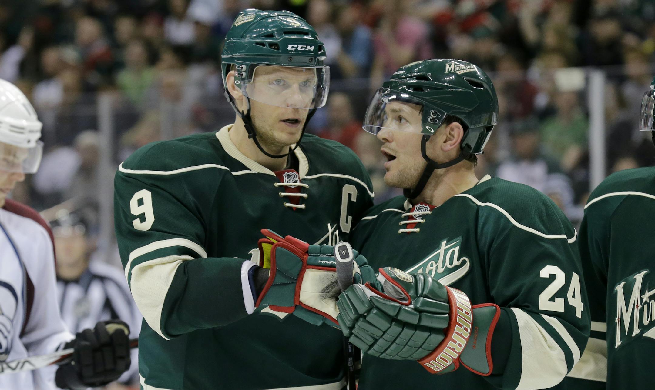 Minnesota Wild center Mikko Koivu (9), of Finland, and Minnesota Wild left wing Matt Cooke (24) talk before a face-off during the second period of Game 3 of an NHL hockey first-round playoff series against the Colorado Avalanche in St. Paul, Minn., Monday, April 21, 2014. (AP Photo/Ann Heisenfelt) ORG XMIT: NYOTK