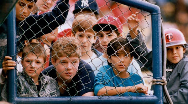 Twins fans peeked through a fence to watch Twins spring training near the dugout at Tinker Field in Orlando in 1988.