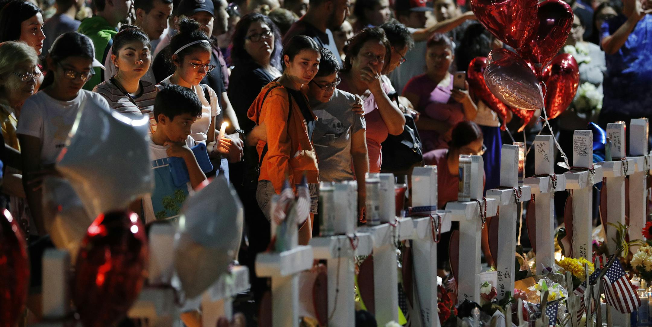 People crowd around a makeshift memorial near the site of a mass shooting over the weekend at a shopping complex, Monday, Aug. 5, 2019, in El Paso, Texas. (AP Photo/John Locher)