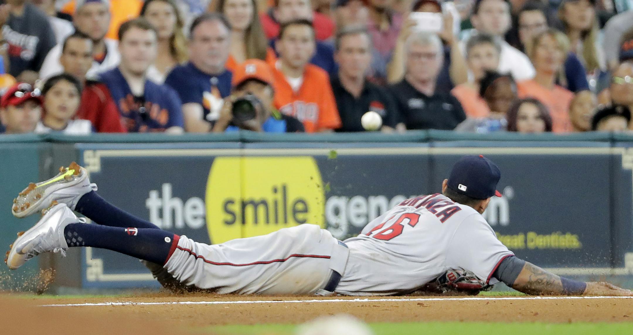 Minnesota Twins shortstop Ehire Adrianza dives while trying to catch a throw from first baseman Kennys Vargas while covering third base during the seventh inning of a baseball game against the Houston Astros, Sunday, July 16, 2017, in Houston. (AP Photo/David J. Phillip)