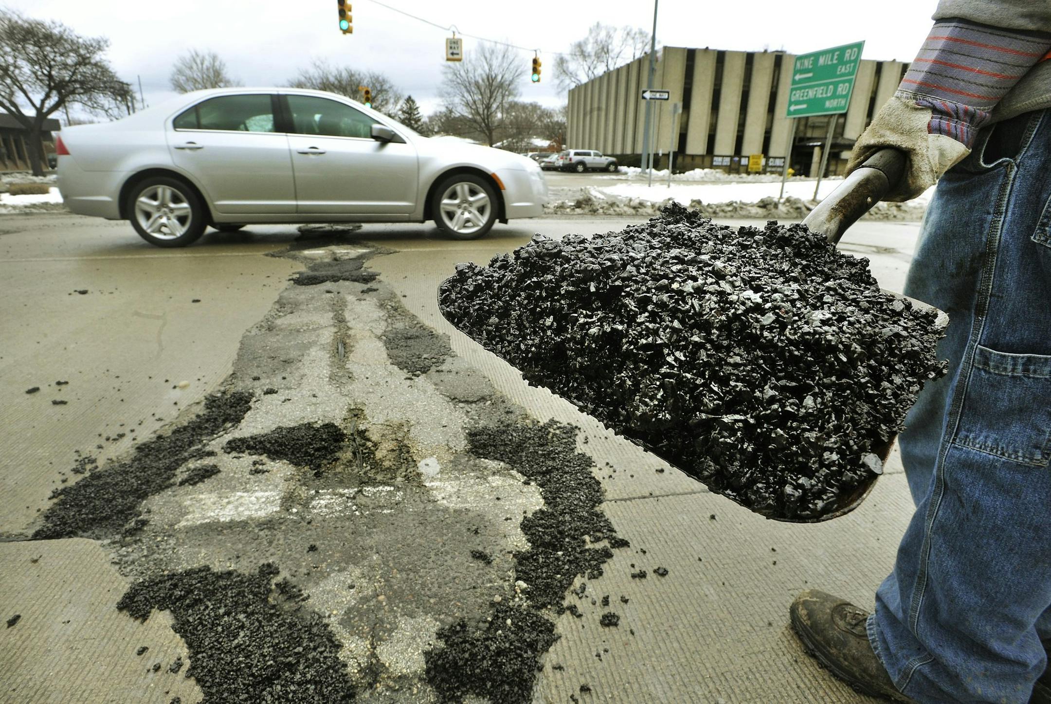 FILE- In a Feb. 28, 2013 photo, Frank Pena waits for traffic to clear to fill potholes on southbound Greenfield Rd., in Southfield, Mich. The Michigan Senate has voted to double the state gasoline tax over four years to raise at least $1 billion to fix roads. Michigan's per-gallon gas tax is a flat 19 cents. A bill approved 23-14 Thursday, Nov. 13, 2014, and sent to the House calls for taxing fuel on the wholesale price. The gas tax would effectively rise to 25 cents in April, 31 cents in 2016,