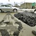 FILE- In a Feb. 28, 2013 photo, Frank Pena waits for traffic to clear to fill potholes on southbound Greenfield Rd., in Southfield, Mich. The Michigan