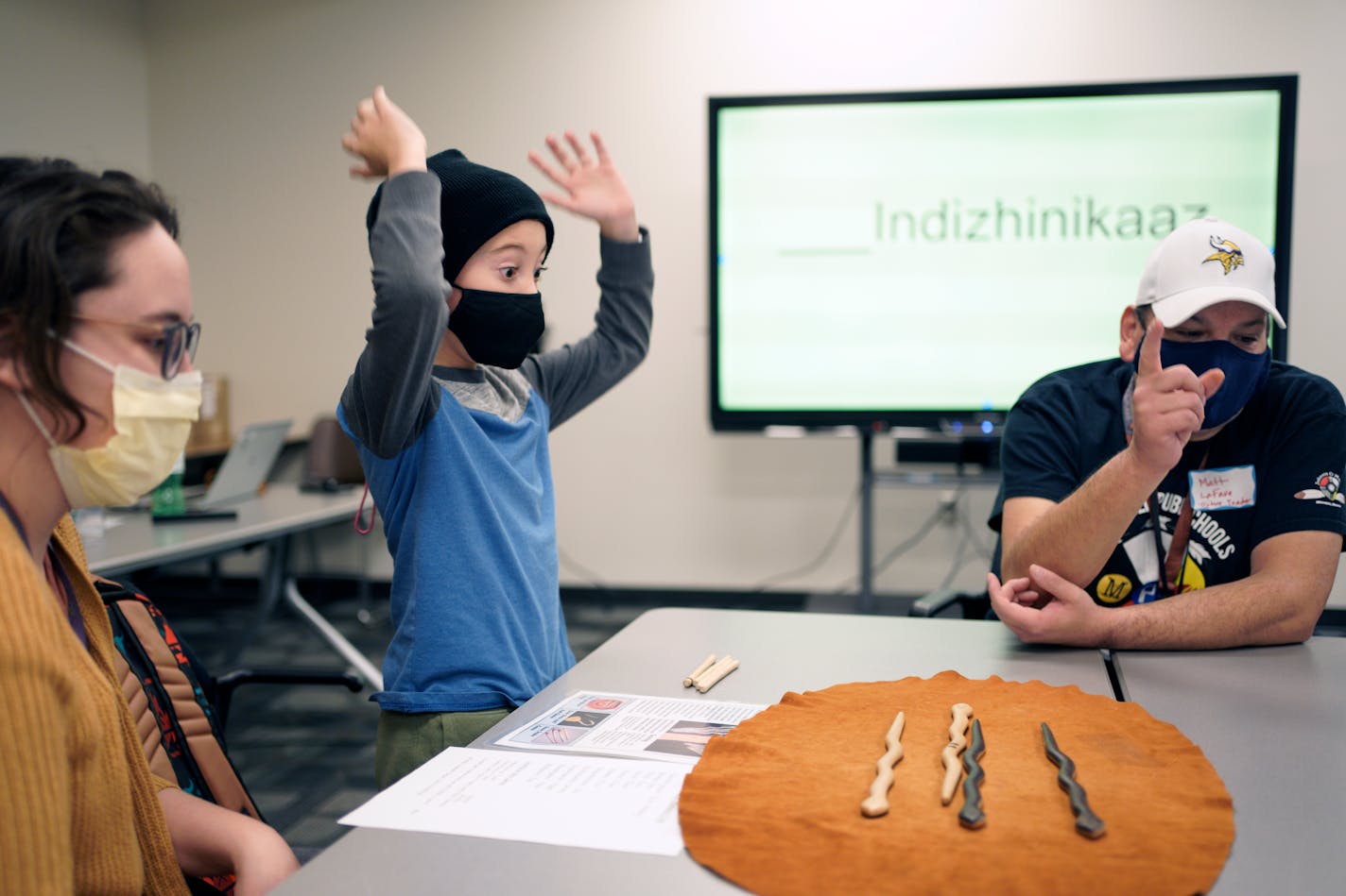 Elliot Nemetz, 8, reacts to winning a round of Four-Stick, an 800-year-old American Indian game. That game was used by American Indian educator Matt LaFave, right, of the Fon du Lac Band, to teach counting to 10 in Ojibwe. Elliot's mother Hannah is at left. Minneapolis Public Schools held several events as part of American Indian Awareness and Family Involvement Week. Wednesday, Nov. 17, 2021 Minneapolis, Minn. ] Brian Peterson ¥ brian.peterson@startribune.com