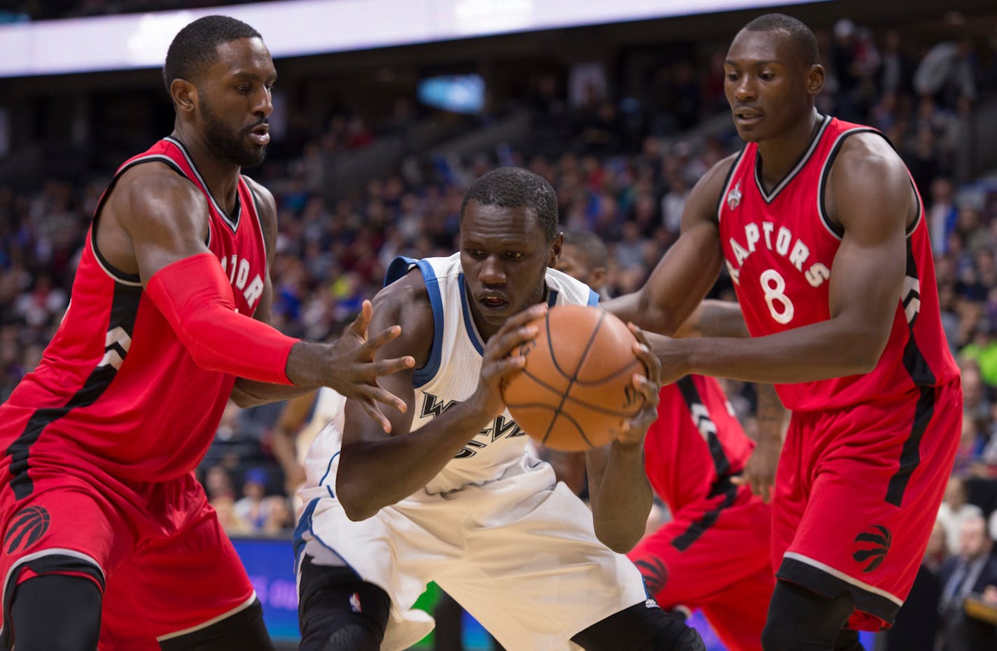 Timberwolves center Gorgui Dieng held the ball under pressure from Raptors forwards Bismack Biyombo, right, and Patrick Patterson during the first half of a preseason game Wednesday. Dieng is determined to add three-point range to his offensive game.