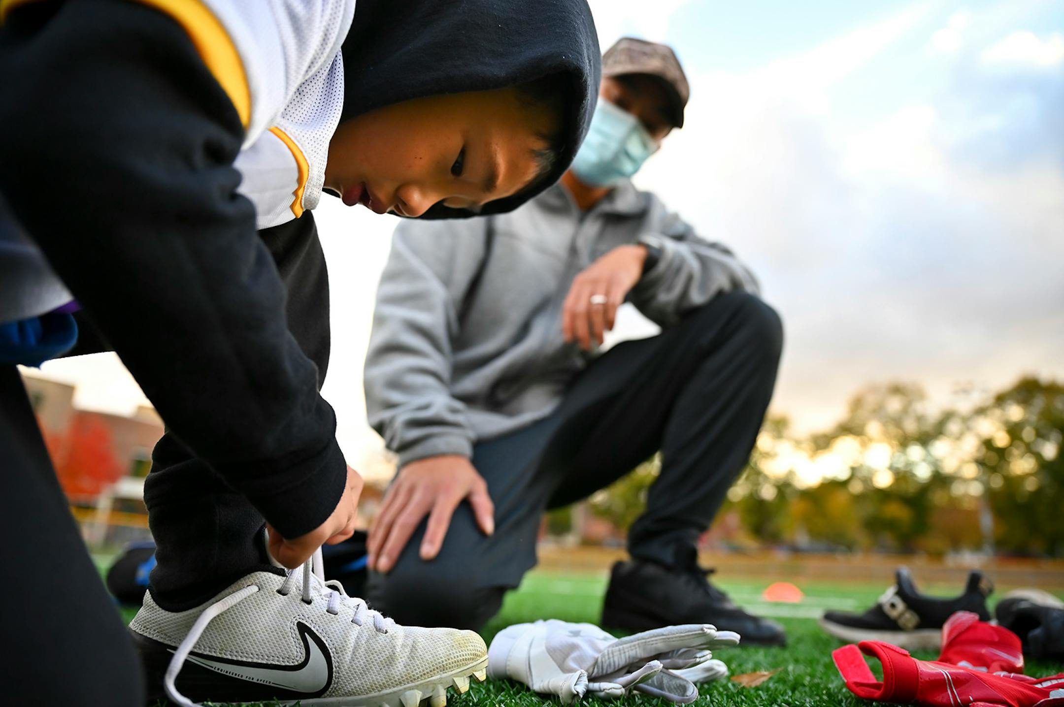 Davis Vue watched as his son Braedus, 6, tied his cleats before flag football practice Wednesday night.