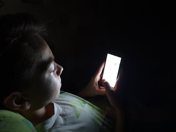 Teen looking at cellphone in dark room.