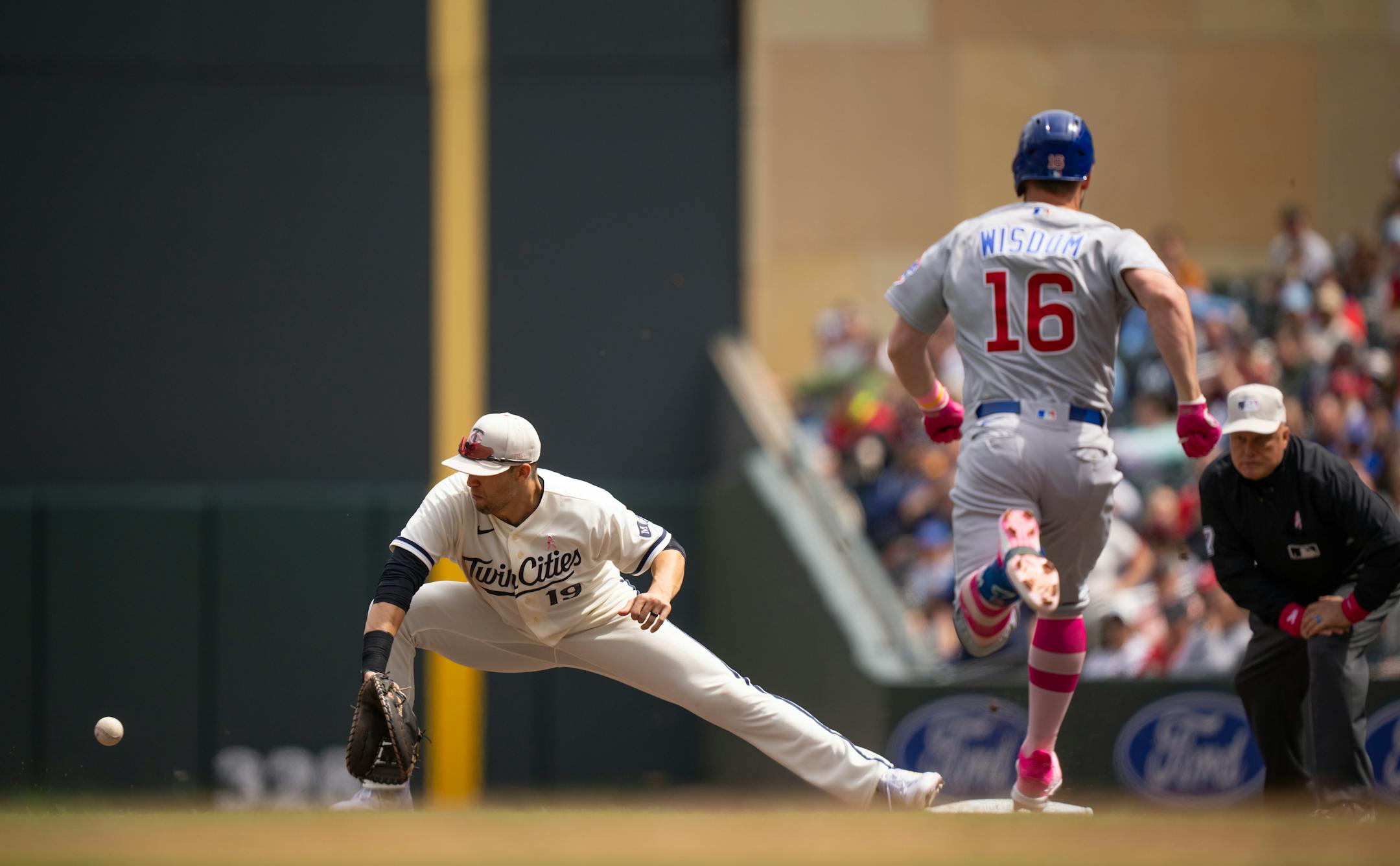 Chicago Cubs third baseman Patrick Wisdom (16) grounded out in the seventh inning as Minnesota Twins first baseman Alex Kirilloff (19) caught the throw from third.