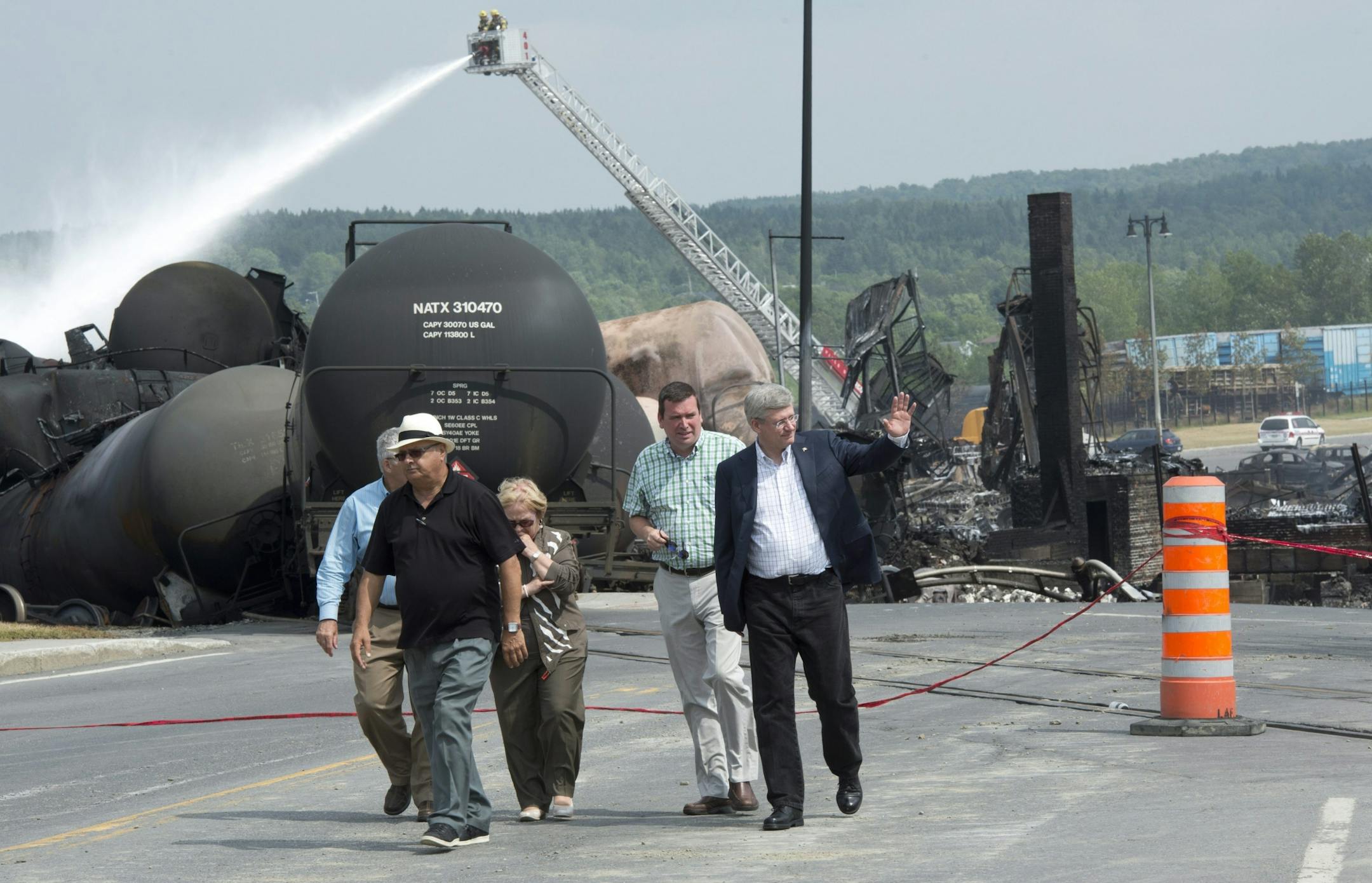 Prime Minister Stepen Harperwaves to people as he visits the site Sunday, July 7, 2013 in Lac Megantic, Quebec, where a runaway train derailed Saturday. Tanker cars carrying oil exploded after the derailment and destroyed the business district in Lac Megantic.