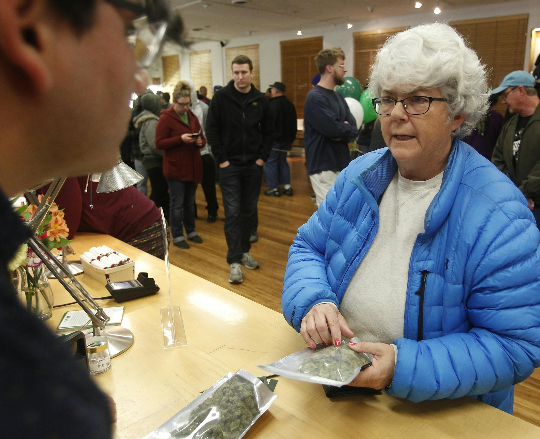 Margot Simpson, right, purchases marijuana at Harborside marijuana dispensary, Monday, Jan. 1, 2018, in Oakland, Calif. Starting New Year's Day, recreational marijuana can be sold legally in California. (AP Photo/Mathew Sumner)