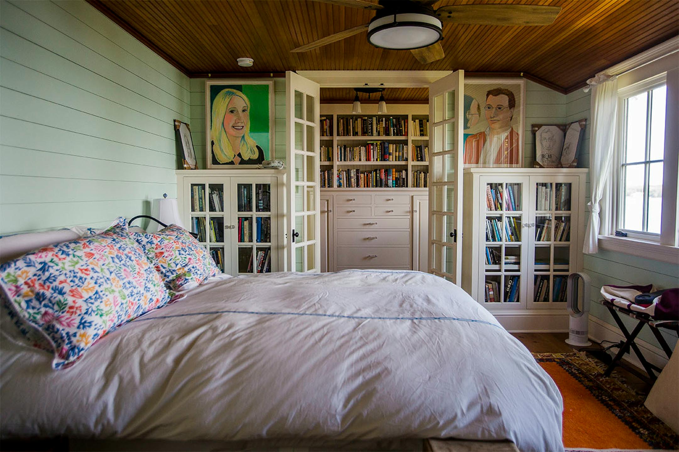 The Moores recycled cabinets from their city bungalow for the cottage's master bedroom. The ceiling is fir beadboard and walls are covered with shiplap boards. The paintings are by Pamela Gaard.