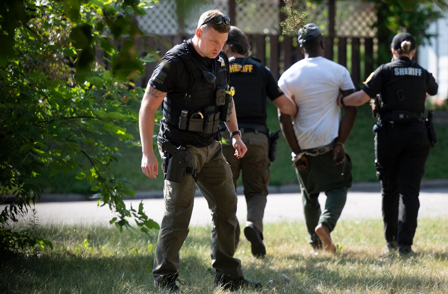 Ramsey County Sheriff's Investigator Kyle Williams, with the department's CATS (Carjacking and Auto Thefts) unit, looks on the ground for evidence after assisting with the arrest of a wanted suspect with a warrant for "theft of motor vehicle" Wednesday, July 19, 2023 on Third Street near Johnson Parkway in St. Paul, Minn.. ] AARON LAVINSKY • aaron.lavinsky@startribune.com