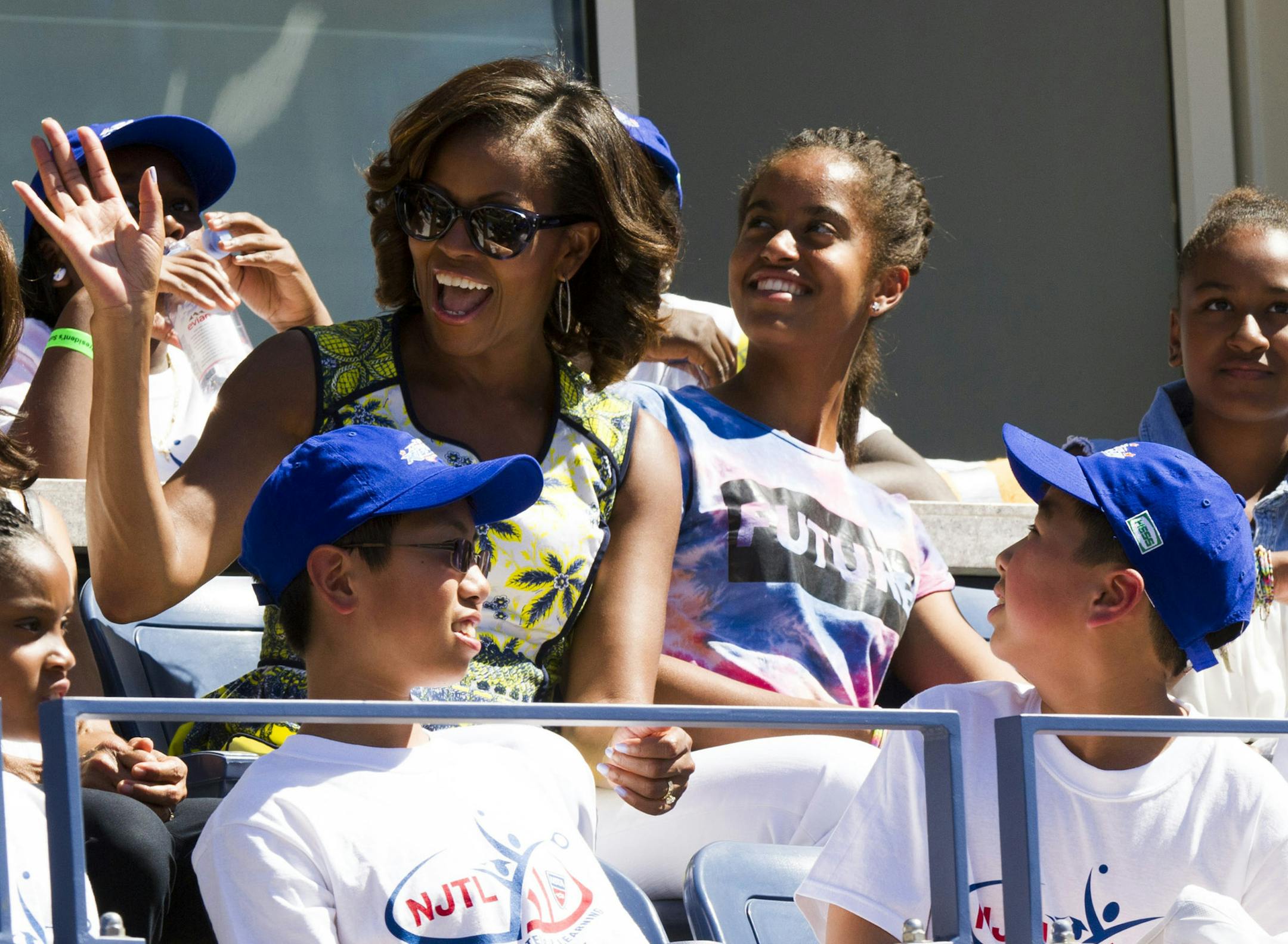 First Lady Michelle Obama , left, alongside her daughters Malia, center, and Sahsa, attend the 18th Annual Arthur Ashe Kidsí Day, the kick off to the 2013 US Open tennis tournament, on Saturday, Aug. 24, 2013 in New York. (Photo by Charles Sykes/Invision/AP)