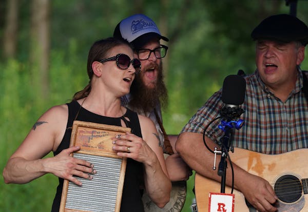 Kim Roe, husband Quillan Roe and gui­tar­ist Dan Gaarder of the Roe Family Singers played in the steamy heat at the Spring­brook Nature Center in F