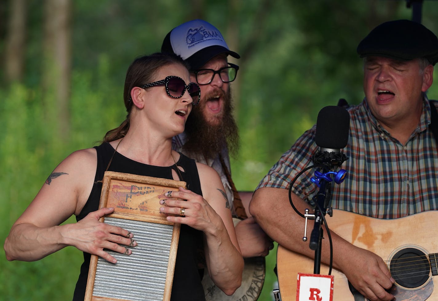 Kim Roe, husband Quillan Roe and gui­tar­ist Dan Gaarder of the Roe Family Singers played in the steamy heat at the Spring­brook Nature Center in Fridley.