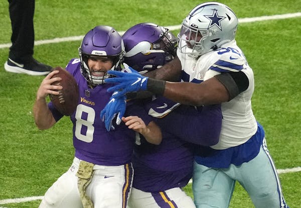 Minnesota Vikings quarterback Kirk Cousins (8) is sacked as offensive tackle Christian Darrisaw (71) is unable to hold off Dallas Cowboys defensive en
