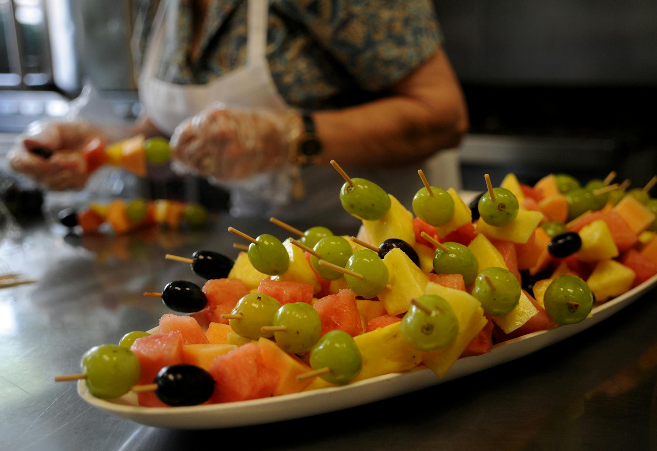Doris Woolsey of One West Catering prepared some fruit skewers getting ready for a funeral meal. Funeral food used to be made by the old ladies in the church basement. Not so much anymore. Many of those post-funeral meals are now catered, offering fancy stuff compared to the egg salad sandwiches of old. ] Richard.Sennott@startribune.com Richard Sennott /Star Tribune. , Minneapolis Minn.Friday 09/07/12) ** (cq)