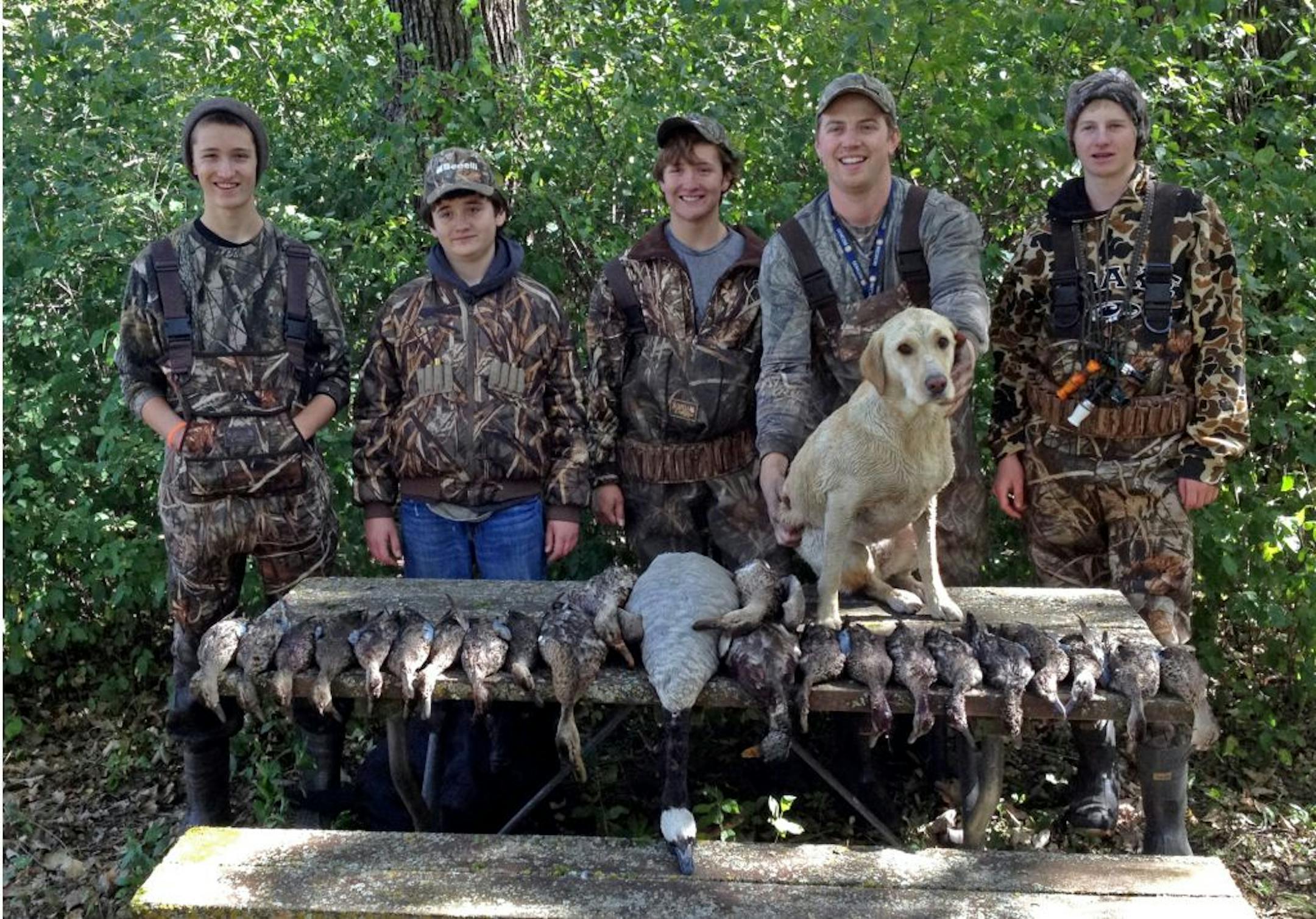 A good opener: Harrison Smith, left, his brothers Parker and Matthew, and cousin, Neil, join Cole Anderson, right, and Neil's Labrador, Jade, with their first-day take of 22 ducks and a Canada goose.