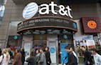 People walk by an AT&T retail store, Monday, Oct. 24, 2016, in New York. AT&T plans to buy Time Warner for $85.4 billion. (AP Photo/Mark Lennihan) ORG