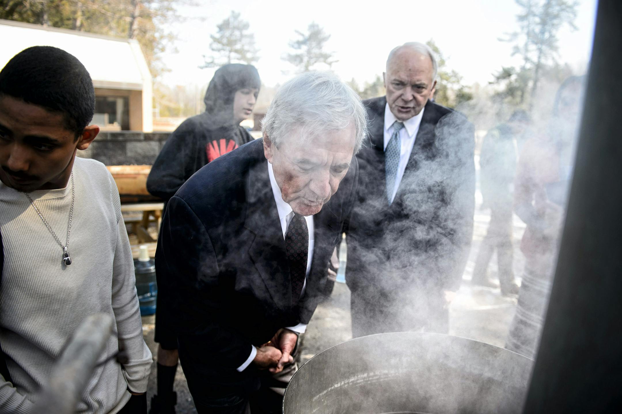 Rep. Rick Nolan and Rep. John Kline leaned in to smell a simmering vat of maple syrup being produced at the school.