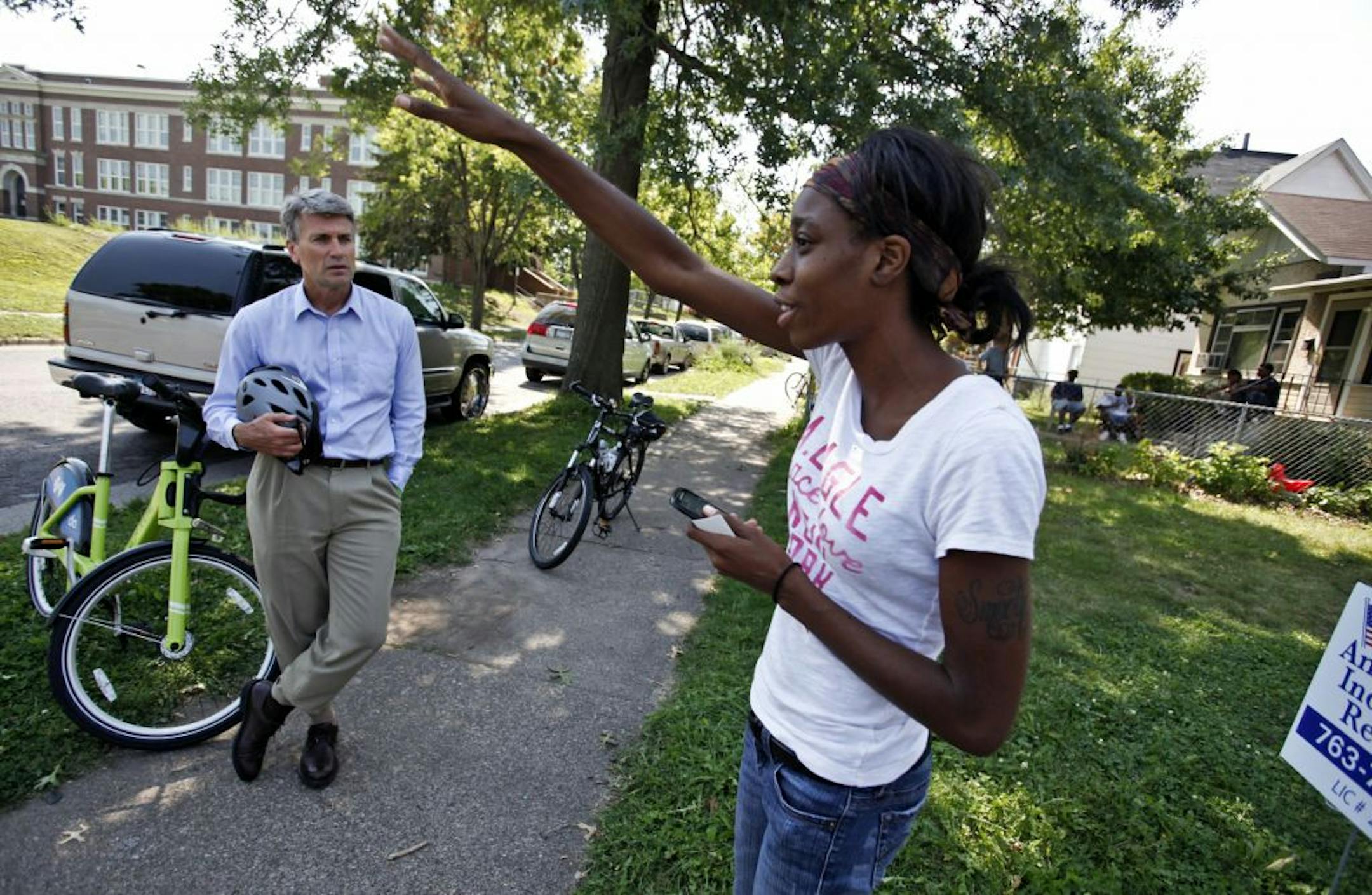 Mayor R.T. Rybak, left, on Friday rode a bike into the area in north Minneapolis racked by gun violence recently. He visited a makeshift memorial set up for 13-year-old victim Ray'jon Gomez and visited with residents. Talking with Rybak was resident Myeisha Kirkwood, right.
