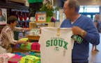 Buck Striebel holds up a University of North Dakota Fighting Sioux T-shirt while his wife, GaeLynn, sorts through other shirts on sale at a sporting g