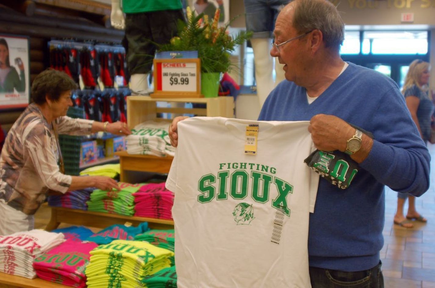 Buck Striebel holds up a University of North Dakota Fighting Sioux T-shirt while his wife, GaeLynn, sorts through other shirts on sale at a sporting goods store in Bismarck, N.D., in 2012.