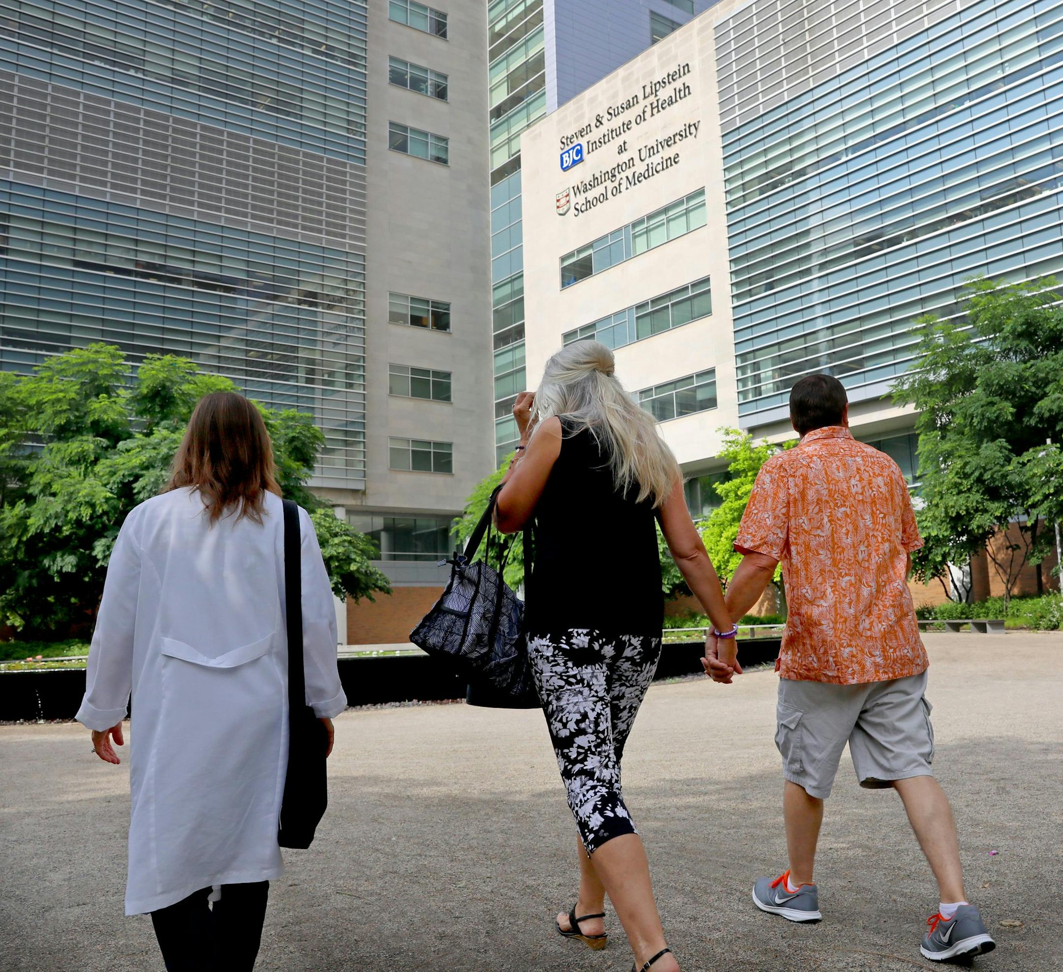 Dean DeMoe, right, and his wife, Deb DeMoe, center, of North Dakota, walk across the campus of Washington University School of Medicine on May 30, 2018, with Tamara Donahue, to begin examinations for a study of people living with dominantly inherited Alzheimer's disease. Dean DeMoe has testing at the medical school yearly as part of the study. Donahue is the study coordinator. (Christian Gooden/St. Louis Post-Dispatch/TNS)