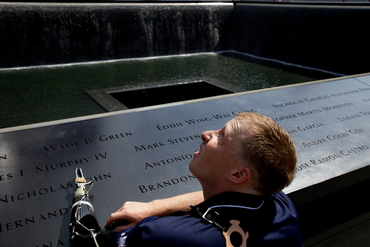 US Marine Cpl. Mark Litynski of New Hope, Minn., looks up at One World Trade while visiting the 9/11 Memorial at ground zero in New York, Wednesday, July 4, 2012. Litynski was visiting the memorial with other wounded veterans as a part of a trip organized by the Stephen Siller Tunnel to Towers Foundation, which is helping to build accessible homes for the wounded veterans. (AP Photo/Seth Wenig)