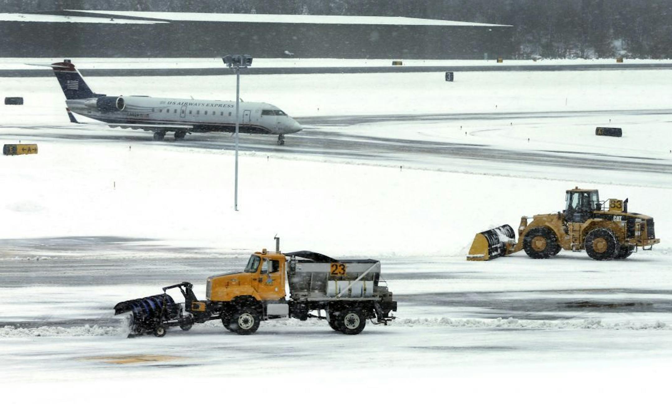Snow is cleared on a runway as a plane taxis into Manchester-Boston Regional Airport in Manchester, N.H., Thursday, Dec. 27, 2012. A muted version of the deadly winter storm that has killed more than a dozen across the eastern half of the country reached the Northeast on Thursday, limiting most of its wrath to travel headaches as Christmas revelers tried to return home.
