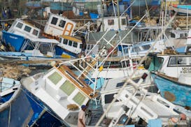 A fisherman looks at fishing vessels damaged by Hurricane Beryl at the Bridgetown Fisheries in Barbados Monday.