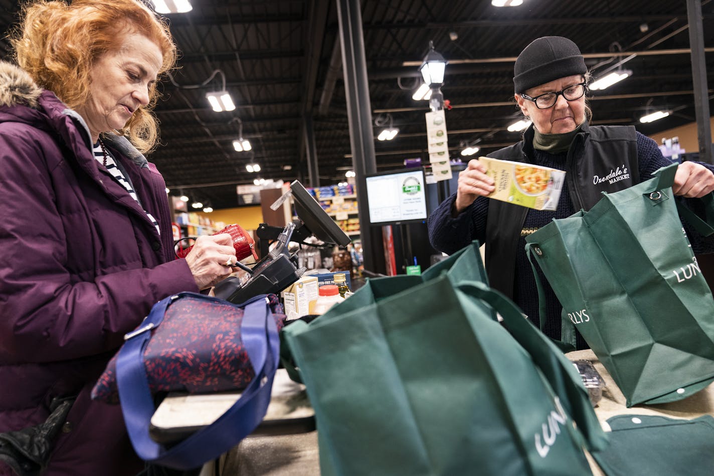 Karla Wagner, right, checked out at Oxendale's Market with her reusable bags with cashier Ilze Bruvelis.