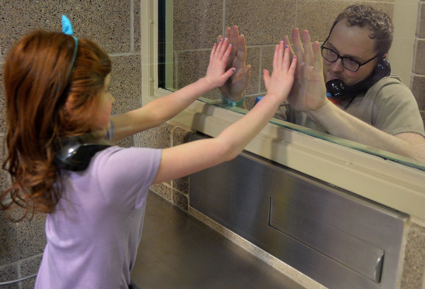 Seven-year-old Maia performs a secret handshake her and her father, Josh, 31, have created during his incarceration at Washington County jail in Stillwater. ] (SPECIAL TO THE STAR TRIBUNE/BRE McGEE) **Maia (7, Minneapolis), Josh (inmate, 31, father)