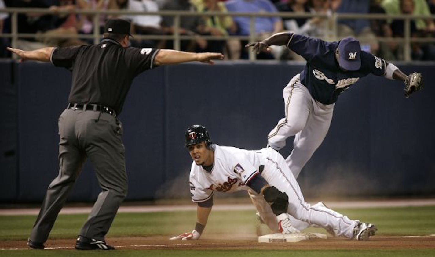 Minnesota Twins center Carlos Gomez slides in safely for a triple, past Milwaukee Brewers third baseman Bill Hall during sixth inning action at the Metrodome.