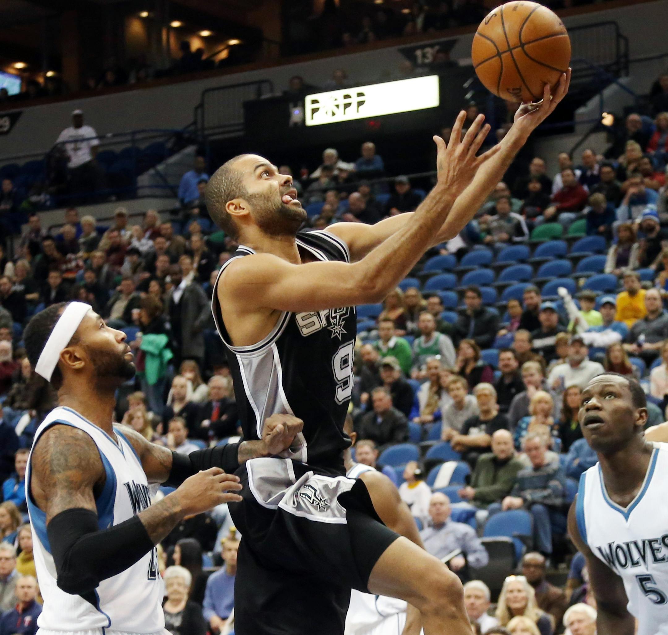 San Antonio Spurs’ Tony Parker (9), of France, lays up a shot as Minnesota Timberwolves’ Mo Williams, left, and Gorgui Dieng, right, of Senegal, watch in the first quarter of an NBA basketball game, Friday, Nov. 21, 2014, in Minneapolis. (AP Photo/Jim Mone)