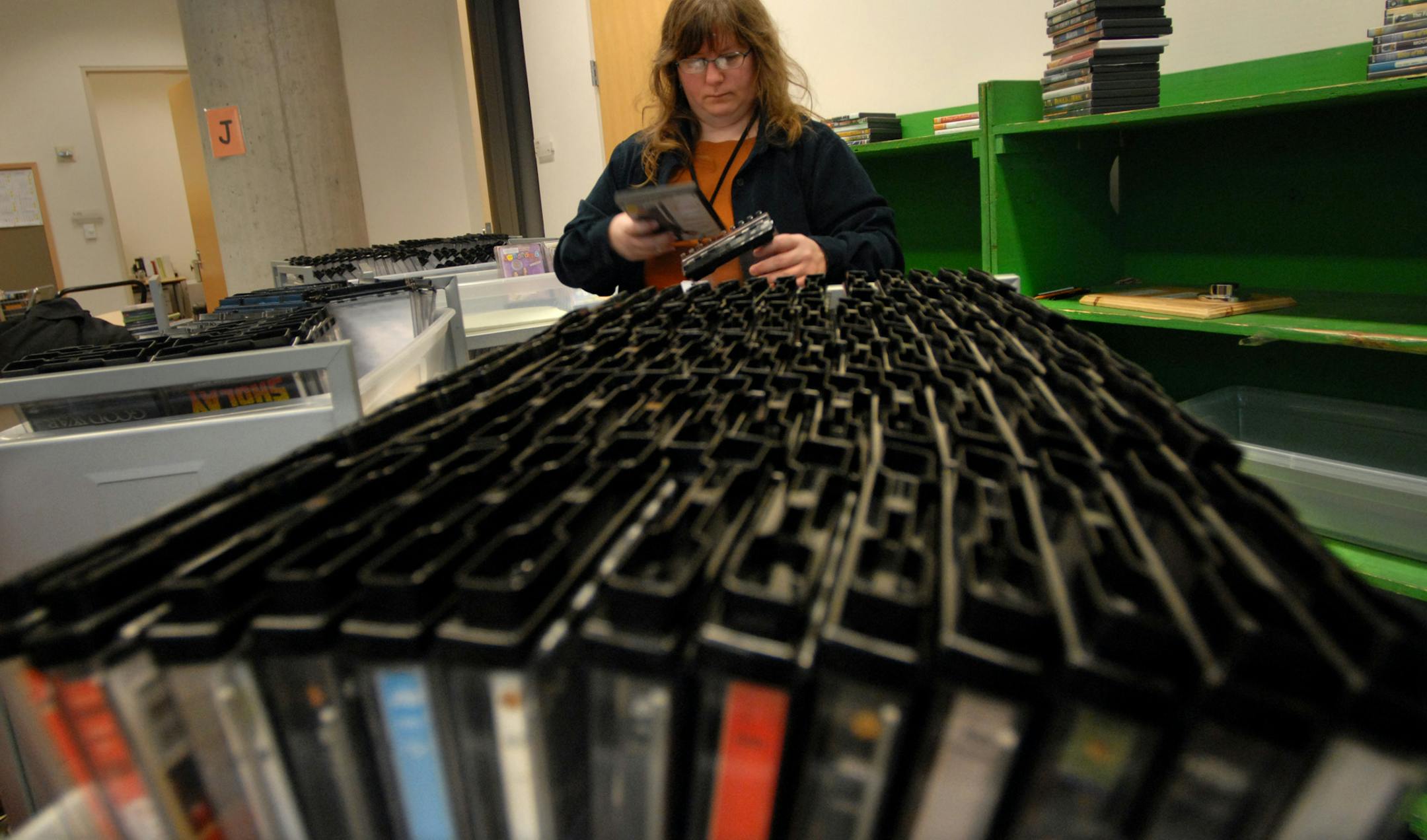 Teresa Mercier sorted through DVD returns at the Minneapolis Central Library. Mercier said that library card holders can check out 10 DVDs at a time for free. Mercier is support services manager.