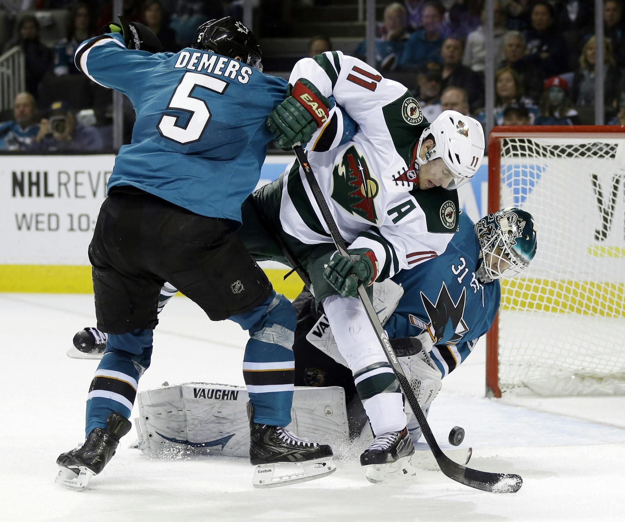 Minnesota Wild's Zach Parise (11) collides with San Jose Sharks' Jason Demers (5) and goalie Antti Niemi (31) of Finland, during the second period of an NHL hockey game on Saturday, Jan. 25, 2014, in San Jose, Calif. (AP Photo/Marcio Jose Sanchez)