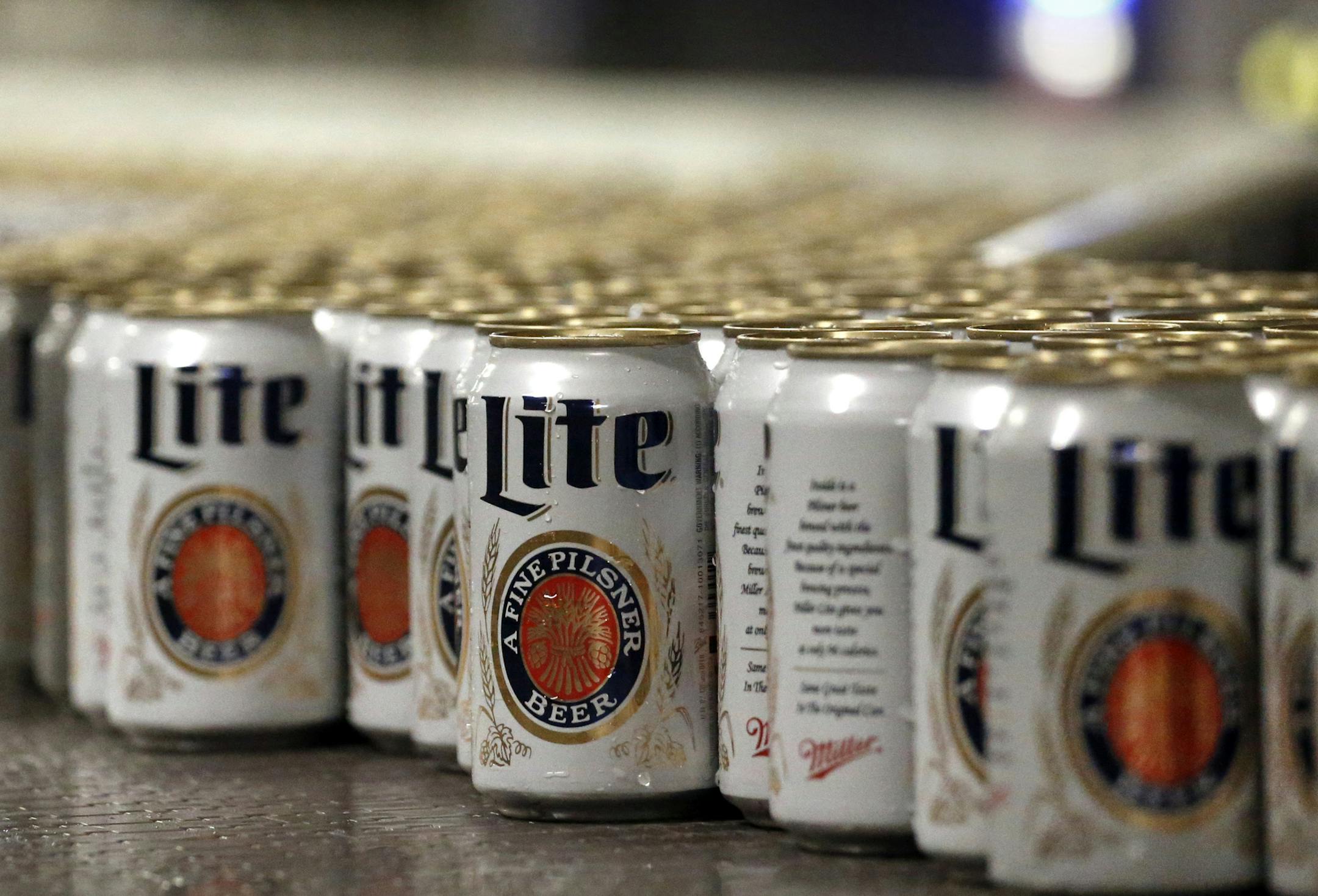 In this March 11, 2015 photo, newly-filled and sealed cans of Miller Lite beer move along on a conveyor belt, at the MillerCoors Brewery, in Golden, Colo. After turning down five offers, British-based brewer SABMiller, which sells beers including Miller Lite, Coors Light and Blue Moon in the U.S. and Puerto Rico through a joint venture with Molson Coors, on Tuesday, Oct. 13, 2015 accepted in principle an improved takeover bid worth 69 billion pounds ($106 billion) from Anheuser Busch InBev. Many