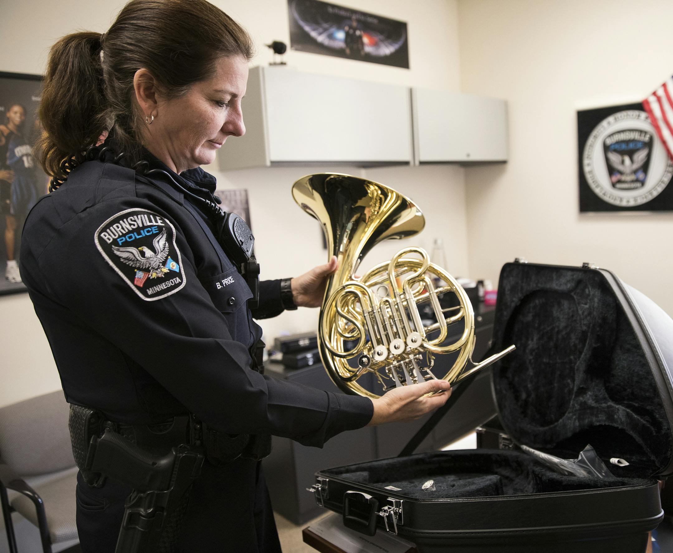 Officer Beverly Price shows off a donated french horn inside her office at Nicollet Middle School in Burnsville] (Leila Navidi/Star Tribune) leila.navidi@startribune.com BACKGROUND INFORMATION: Officer Beverly Price looks through instrument donations in her office at Nicollet Middle School in Burnsville on Tuesday, December 13, 2016. Nicollet Middle School received donations of 15 musical instruments for band classes from the Manilow Music Project.