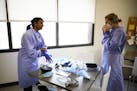 Dr. Geetha Damodaran, left, suited up with PPE (Personal Protective Equipment) before the start of a volunteer shift at Hope Dental Clinic Thursday al