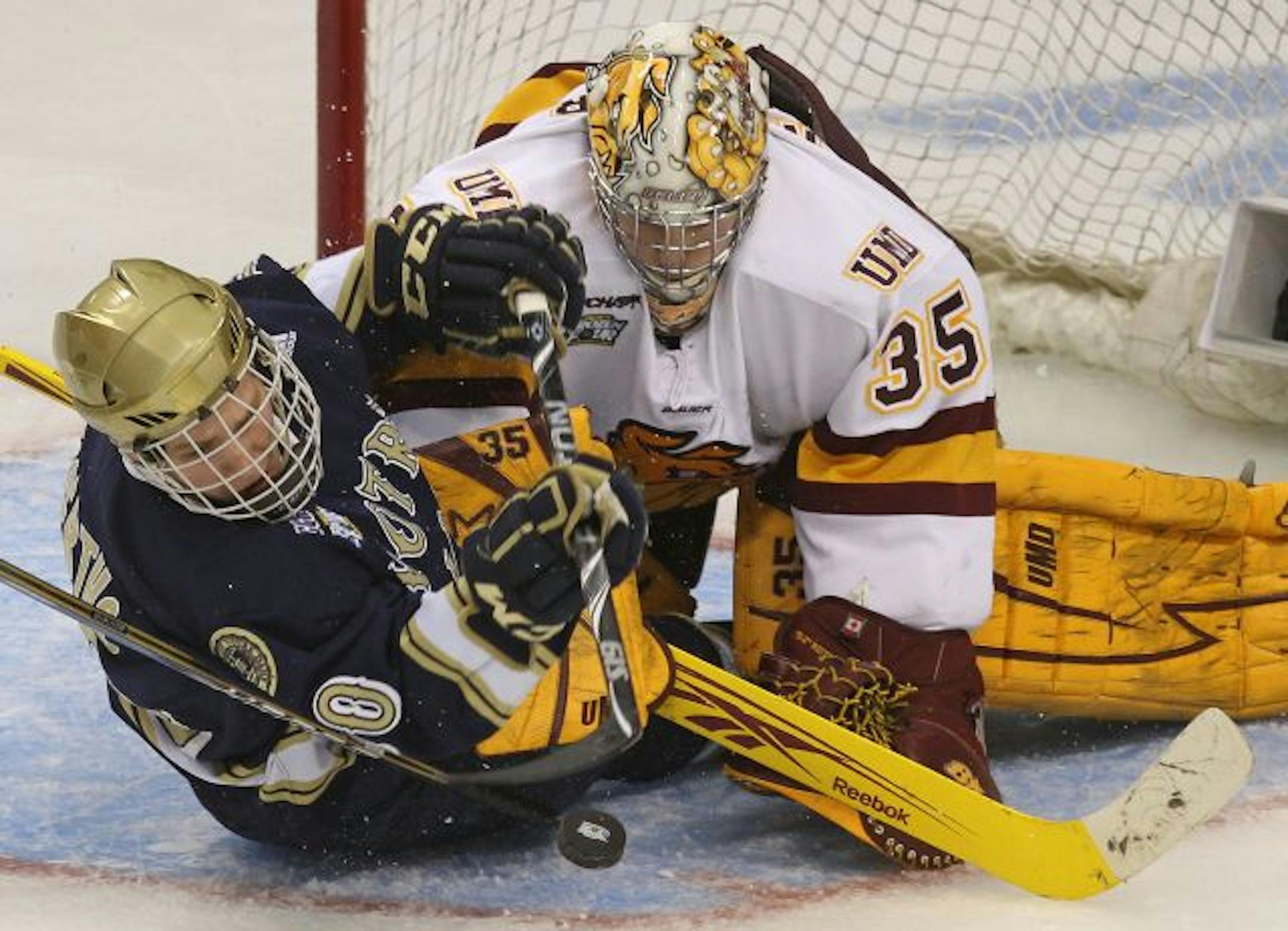 NCAA Frozen Four Semifinals, Minnesota Duluth vs Notre Dame. (left to right) Notre Dames David Gerths and Duluth goalie Kenny Reiter battled for a loose puck.